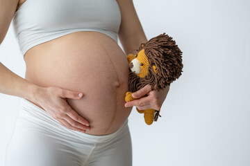 Abdominal shot of a cuddly toy lion being held by the mother, who is looking excitedly at her bare,...