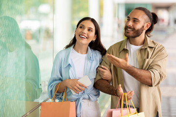 Cheerful inspired millennial caucasian guy and woman with bags enjoy shopping and spare time