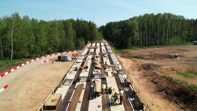 Construction team in hard hats work at the construction site aerial view. Concrete structure. Builders in the process of work. Construction of an overpass and a bridge.