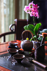 Tea set on the wooden table in authentic vintage style with orchid flower at the background - dark und moody photography