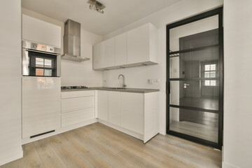 a kitchen with white cabinets and wood flooring in the middle part of the room, there is an open door leading to the