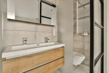 a modern bathroom with wood cabinets and white tiles on the walls, along with a toilet in the middle part of the room