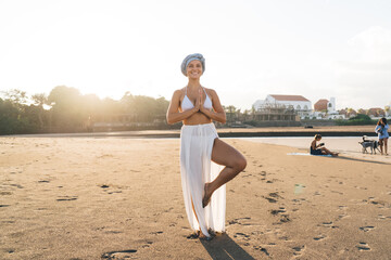 Fototapeta na wymiar Happy woman meditating on sandy beach in tree pose