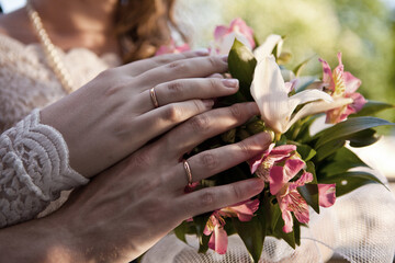 Wedding rings on fingers. Newlyweds with a bouquet of flowers