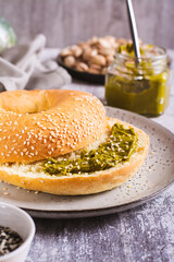 Bagel with pistachio cream butter for breakfast on a plate on the table vertical view