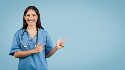 Smiling young female nurse pointing to side at free space