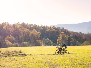 Recreational cycling couple enjoying the scenery of a rural area while riding bikes on the country road. Nature, tourism, and active vacation concepts.