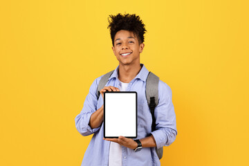 Happy black male student holding tablet with blank screen