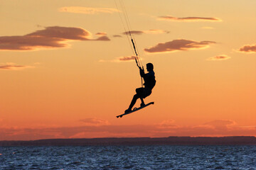 Kitesurfer fly in the air at colorful sundown