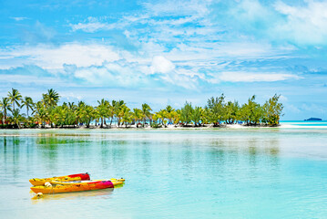 Brightly colored kayaks, an idyllic lagoon and a sand bar with palm trees sums up the tropical paradise of Aitutaki in the Cook Islands. - obrazy, fototapety, plakaty