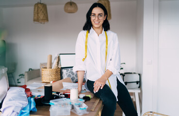 Smiling dressmaker on table in workshop