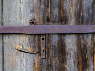 Old door with a rusty lock and bar.