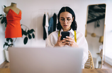 Focused woman using smartphone in atelier