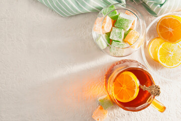 Oriental sweetness Turkish delight and tea with lemon. The bowls contain sweets and sliced lemon. In a transparent mug there is hot black tea with a slice of lemon. 