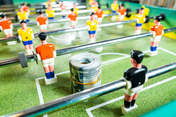 Table football figures close-up with rolled up dollar bills. Foosball table soccer. Sport and competition concept