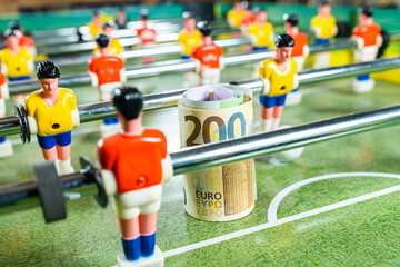 Table football game with a roll of euro bills in front of a red player, concept of betting and victory, sports money