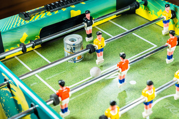 Table football game with rolled up dollar bills placed in front of the gates and goal keeper,...