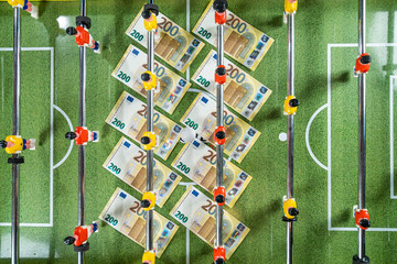 Table Soccer or Foosball Kicker Game, Top View on the 200 euro banknotes under the players figures, money rules sports - obrazy, fototapety, plakaty