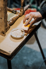 Male professional worker carpenter, woodworker improves tool with plastic spatula putty, cement a wooden chair in the workshop. Photography, handmade concept, lifestyle.