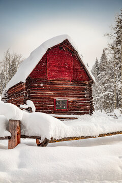 Abandoned red barn in winter scene covered in snow
