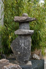 Fototapeta na wymiar Vertical shot of a stone with Japanese characters with trees in the background