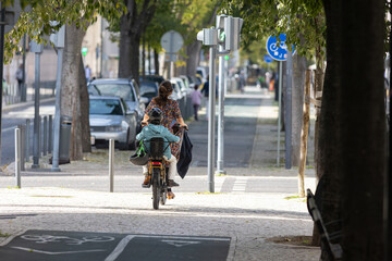 A woman with child riding a bike down a street