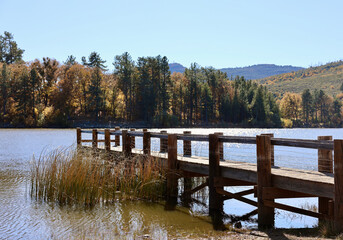 wood fishing dock leading out onto the lake
