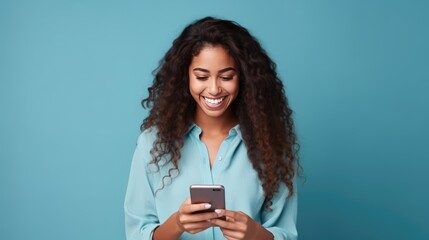 Radiant woman with dark skin in a blue shirt, beaming at her phone against a vivid blue backdrop, exuding joy