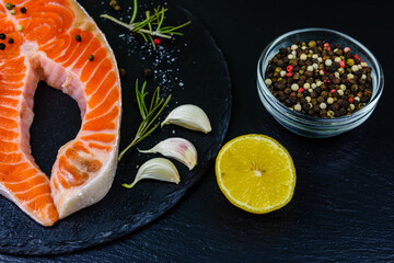 Raw salmon steak and spices on a slate board