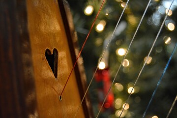 close-up of a harp with a heart carved into it, with lights blurred in the background.