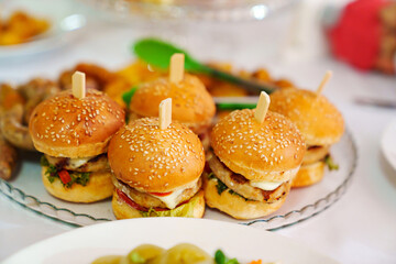Mini burgers on a plate with french fries and sausages. 