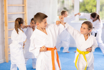 Children in kimono practicing karate in a sports gym. Martial arts training session