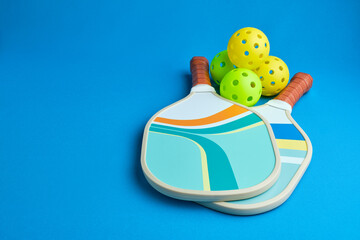 yellow and green pickleball paddles and balls on blue background