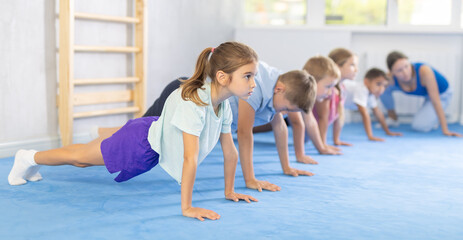 Purposeful boys and girls athlete before training martial arts performs exercises press-up....