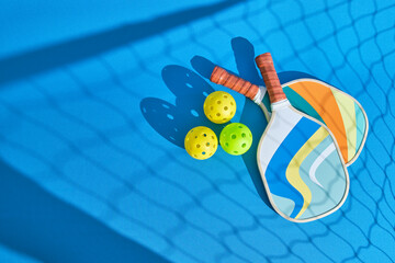 image from above of two pickleball paddles on the ground with the shadow of the net in front
