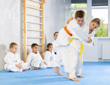 Young boys and girls athletes in white kimonos practice Brazilian jiu Jitsu Aikido Wing chun wrestling. Training at Academy of Martial Arts martial arts hand-to-hand combat.