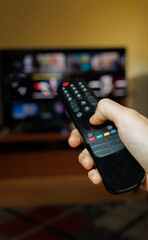 hand holding a TV remote control to change channels and different platforms