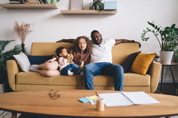 Serious diverse family sitting together on sofa in living room