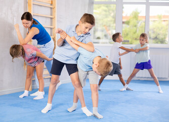 Fototapeta premium Young children, boy and girl, working in pair mastering new self-defense moves at gym