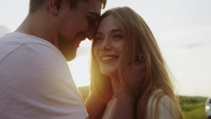 Close-up view of a lovely couple standing facing each other on a background of sunset. Romantic moments.