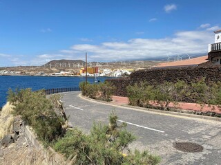 Narrow coastal road for cars with a ship on the water surface in the background