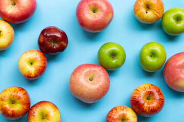 Variety of fresh apples on blue background.