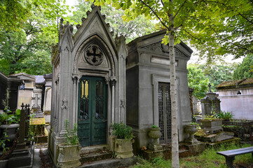 Paris, France. June 30, 2022. The characteristic and historic Père-Lachaise cemetery, two dark-looking family tombs. Many personalities are buried here.