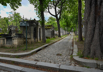 Paris, France.June 2022. The characteristic and historic cemetery of Père-Lachaise, shoot at the crossroads of one of the avenues bordered by large old trees. Many personalities are buried here