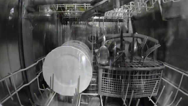 Dishwasher while washing dishes. Inside view