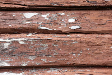 Old brown color on wooden horizontal plank facade. Torn and worn outside. 