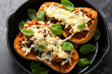 Baked Butternut Squash Pumpkin Stuffed with ground beef, vegetables and cheese in iron cast pan