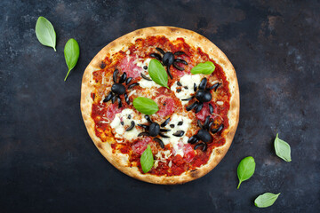 Traditional Italian Halloween spider pizza with salami, mozzarella and olives served as a top view...