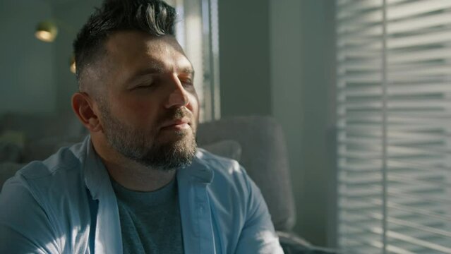 Portrait of handsome man breathes in air, looks out window, enjoys great morning. Gray haired male feeling happy looking out the window at sun shine. Cinematic shot of man 40s lifestyle casual look 4K