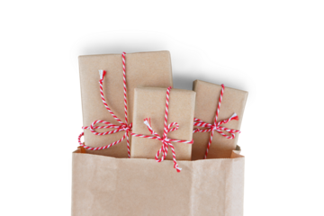 Christmas gift boxes wrapped in craft paper with striped red and white baker's twine in brown recycled paper bag isolated on white, transparent background, PNG. Flat lay, top view